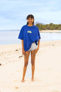 Femme portant le t-shirt bleu oversize Loli Seaside en coton avec design vert fluo