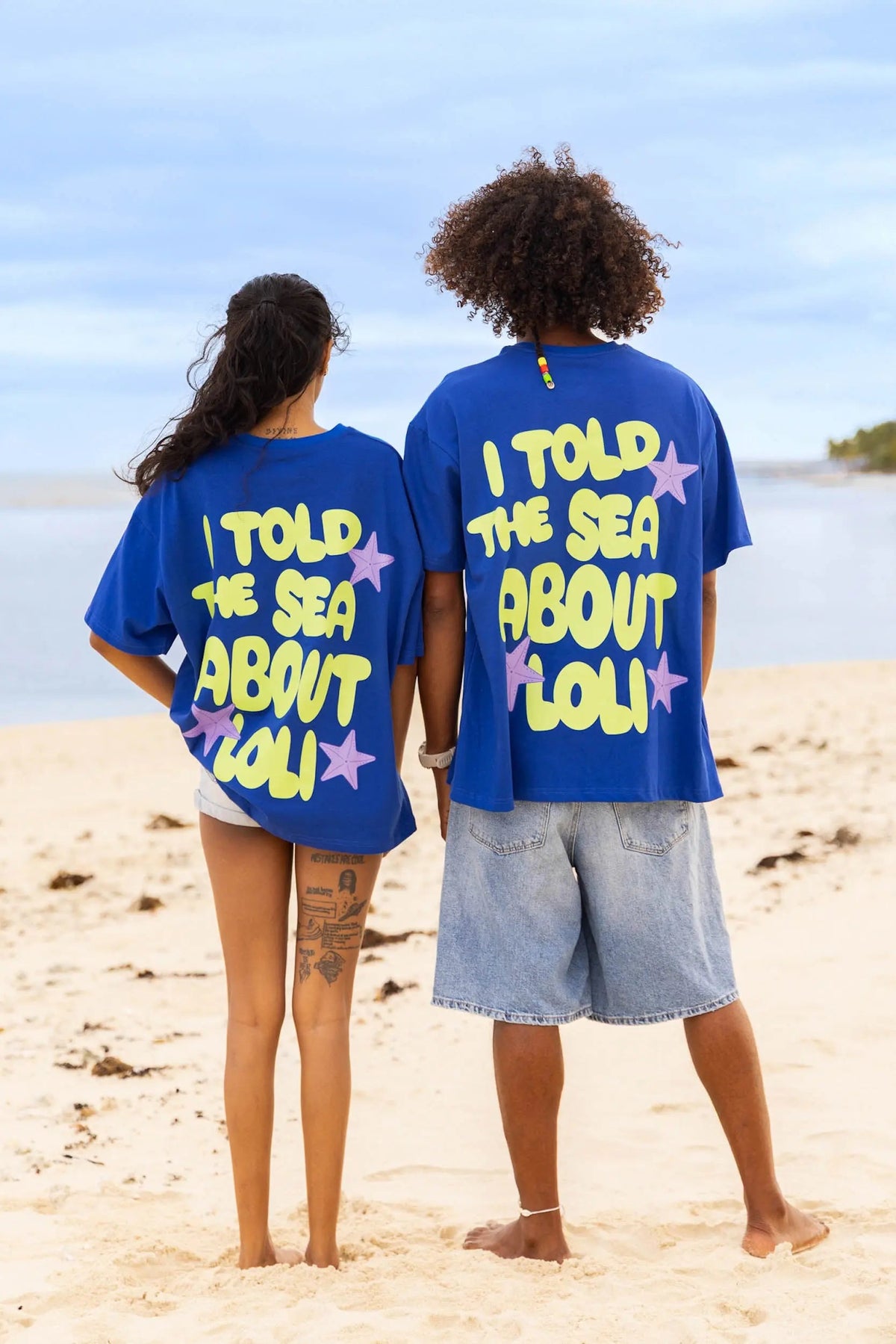 Femme et homme de dos portant le t-shirt bleu en coton Loli Seaside avec gros imprimé coloré 